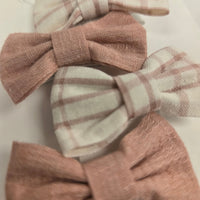 Three fabric hair bows in plaid and solid colors on a light background