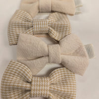 Set of four beige and brown patterned hair bows on a white background